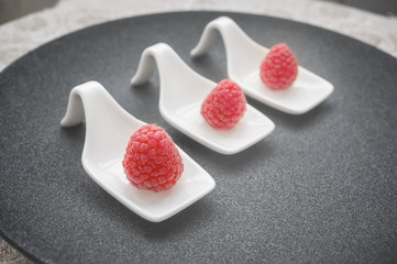 Ripe raspberries in a white dish plate. The concept of healthy eating. Selective focus