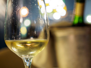 Macro closeup detail of a glass of Alsatian white wine at a romantic restaurant dinner. Shallow focus, bucket and chilled bottle in background. Colmar, France. Food and drinks. - 262512929