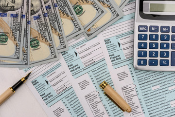 Dollars with pen, calculator and 1040 form