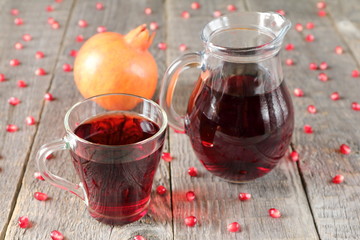 A mug of pomegranate juice on a grey wooden background.