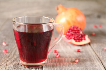 A mug of pomegranate juice on a grey wooden background.