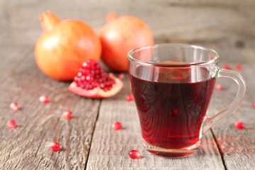 A mug of pomegranate juice on a grey wooden background.