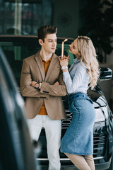 cheerful blonde girl looking at handsome man standing with crossed arms