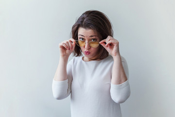 Simple studio portrait of hipster fashion smiling short-haired brunette girl in trendy yelow sunglasses isolated on white background. Fun positive young smart woman in glasses having fun smiling