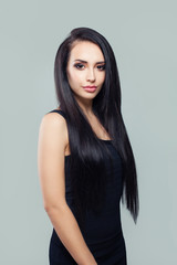 Elegant woman with long healthy straight hair and makeup wearing black dress