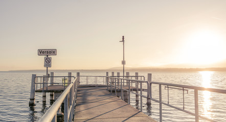 Long jetty at the lake. Sunrise and mountains.