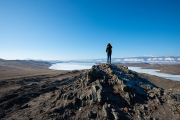 Landscape of women tourists standing on the rocky mountain and frozen Baikal lake view in Russia