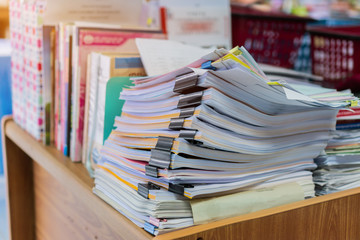 Piles unfinished documents reports files with overwork paper corner on teacher school desk office at university of Thailand. Stack of messy paperworks assessment legal folder at workplace concept