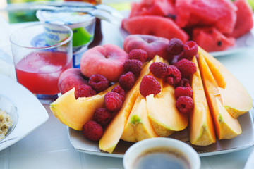 Traditional breakfast is fragrant black coffee with fresh fruits, watermelon and melon on the table. 