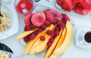 Traditional breakfast is fragrant black coffee with fresh fruits, watermelon and melon on the table. 