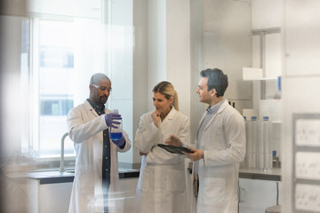 Team of scientists discussing experiment data on digital tablet