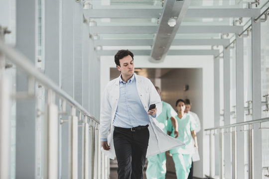 Doctor Using Pager In Hospital Corridor