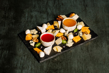 Cheese plate on a black table. Many kinds of cheese on a plate