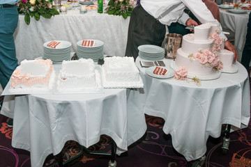 Restaurant waiter serving dessert table with wedding cakes.