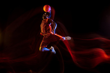 One moment to win. African-american young basketball player of red team in action and neon lights...