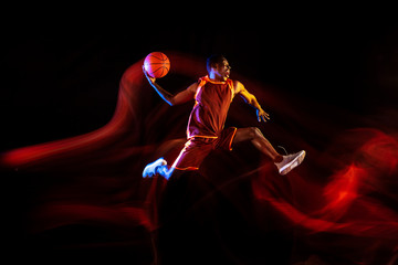 Emotions of winner. African-american young basketball player of red team in action and neon lights...