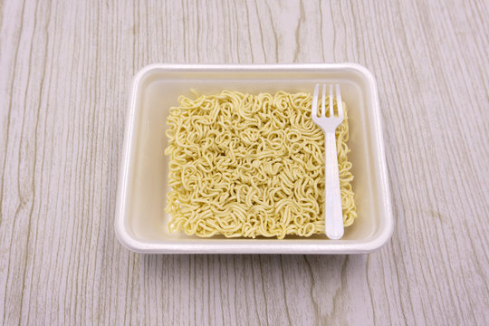 Instant noodles in a plate on a black background. Fast food, junk food, unhealthy food. Rolton Doshirak