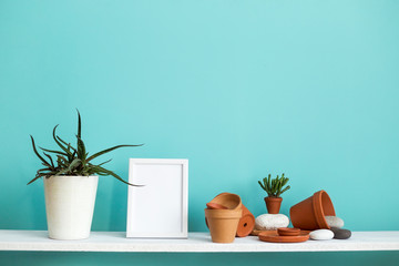 White shelf against pastel turquoise wall with pottery and succulent plant with potted succulent plant.