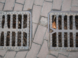 two city sewer grids on a pavement for rain water flows to prevent flood