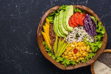 Fototapeta na wymiar Healthy vegan superfood bowl with quinoa, wild rice, chickpea, tomatoes, avocado, greens, cabbage, lettuce on black stone background top view with copy space. Food and health