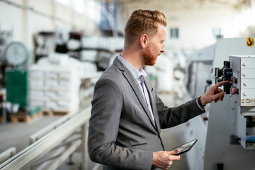 Manager checks machines at the factory.  Supervisor runs his daily check at work. Factory worker setting the tech up for work.