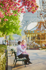 Couple under blooming cherry tree on a spring day with Eiffel tower