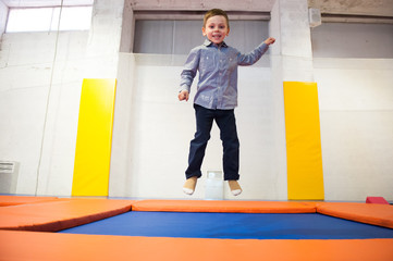 happy smiling small kid jumping on indoors trampoline during leisure sport training
