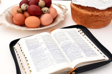Brest, Belarus - April 17, 2019: Open book Bible, Easter cake, painted eggs. Christianity, Easter.