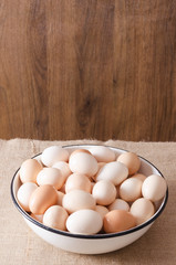 Vertical shot.A big bowl full of eggs.Lot of eggs in the metal bowl against wooden background.Empty space for your design