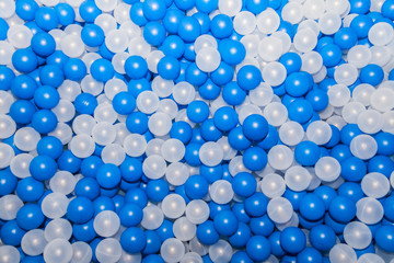 Top view of plastic white and blue balls in dry pool on the playground