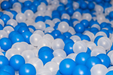 Plastic white and blue balls in dry pool on the playground. Selective focus and perspective view