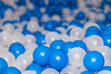 Plastic white and blue balls in dry pool on the playground. Selective focus and perspective view