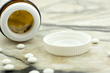 Closeup many Vitamins C tablet in front of open lid bottle in white isolated background .