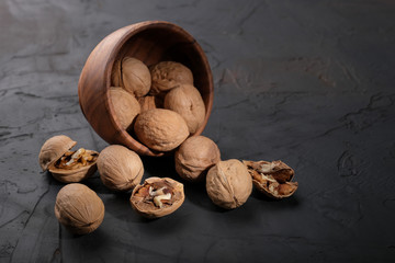 Walnuts in a wooden cup on a dark background.