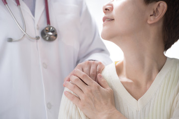Medical doctor reassuring senior patient and putting a hand on patient’s shoulder