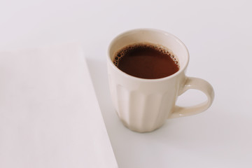 A coffee cup and a notebook. Business breakfast on white background. Flat lay, top view, office desktop 