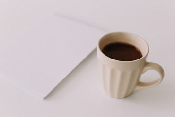A coffee cup and a notebook. Business breakfast on white background. Flat lay, top view, office desktop 