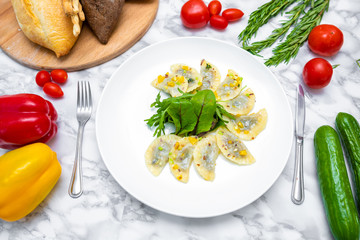 Dumplings, filled with cabbage. vegetable dumplings. Dumplings with potatoes in plate on white background. Ingredients for dumplings with cabbage, potatoes, tomato, cucumber, lettuce, pepper. Top vie