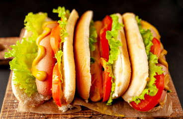 three hot dogs on a cutting board against a background of stone