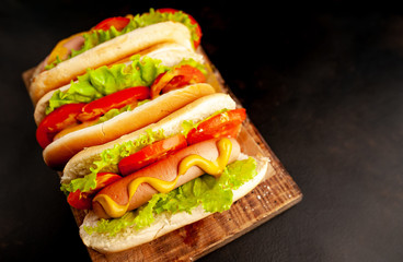 three hot dogs on a cutting board against a background of stone