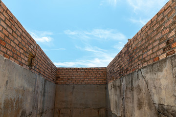 Perspective view of abandoned old outdoor concrete orange brick wall on sunny day with clear blue sky during summer time.