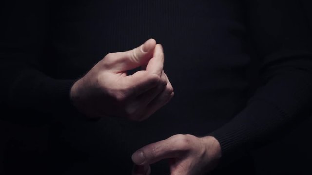 Male hand making money asking sign gesture rubbing fingers together on black background