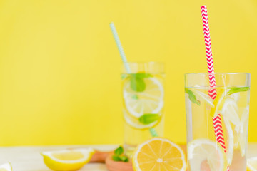Homemade lemonade with lemon and mint on colored yellow background. Summer cold drink cocktail. Copyspace