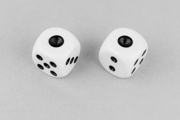 Two white dices on gray background top view, one and one