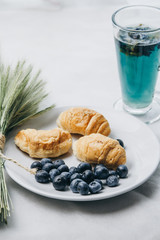 healthy light breakfast. Blue tea from orchids, blueberries, croissants on a plate with spikelets of wheat. Ingredients for yogurt. proper nutrition for a slim figure. raw food vegetarianism. diet