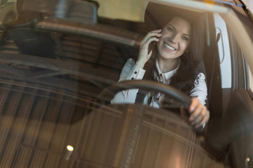 Happy woman buyer sitting in her new vehicle in car dealership