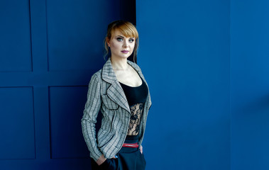 business girl in strict clothes standing near a wall with glasses