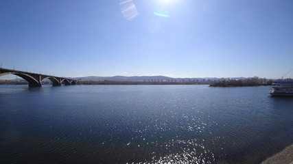 Beautiful cityscape, big river, stone bridge, ship. In the distance are mountains, trees and houses.