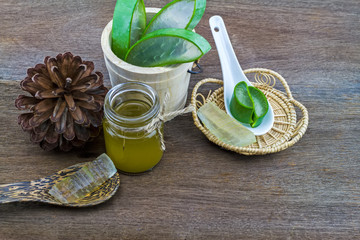 Fresh aloe vera gel on ceramic  spoon with aloe  vera essential oil and pine   on wooden table