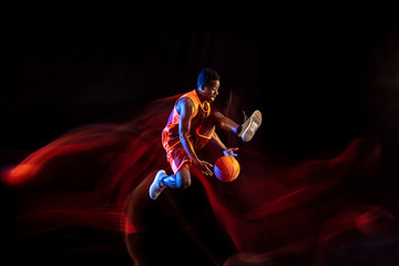 Slam dunk. African-american young basketball player of red team in action and neon lights over dark...